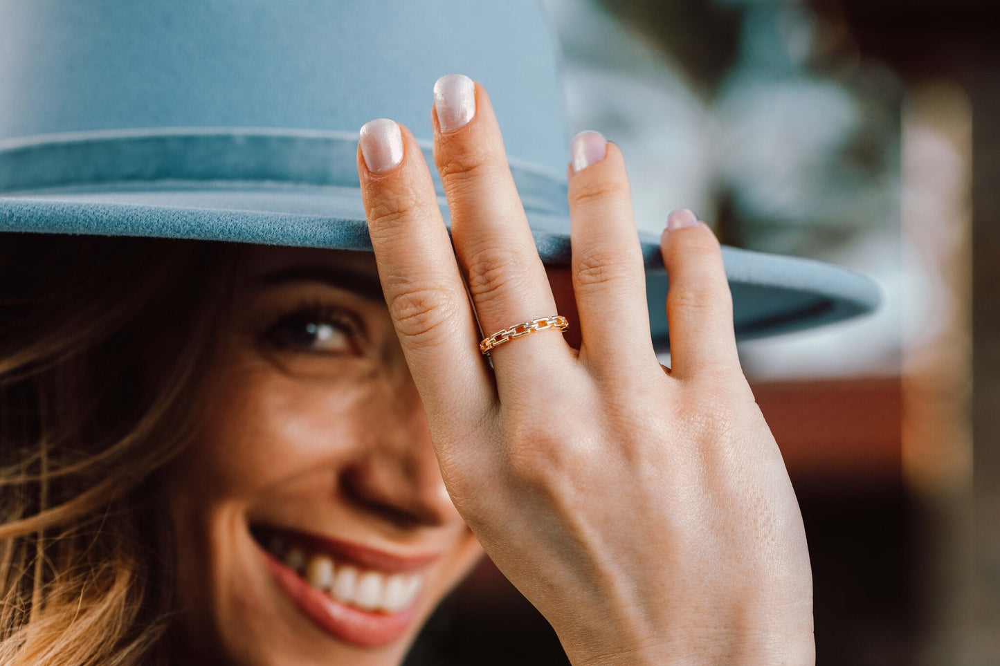 Model wearing the 14K gold Heart Ring, lifestyle shot with blue hat