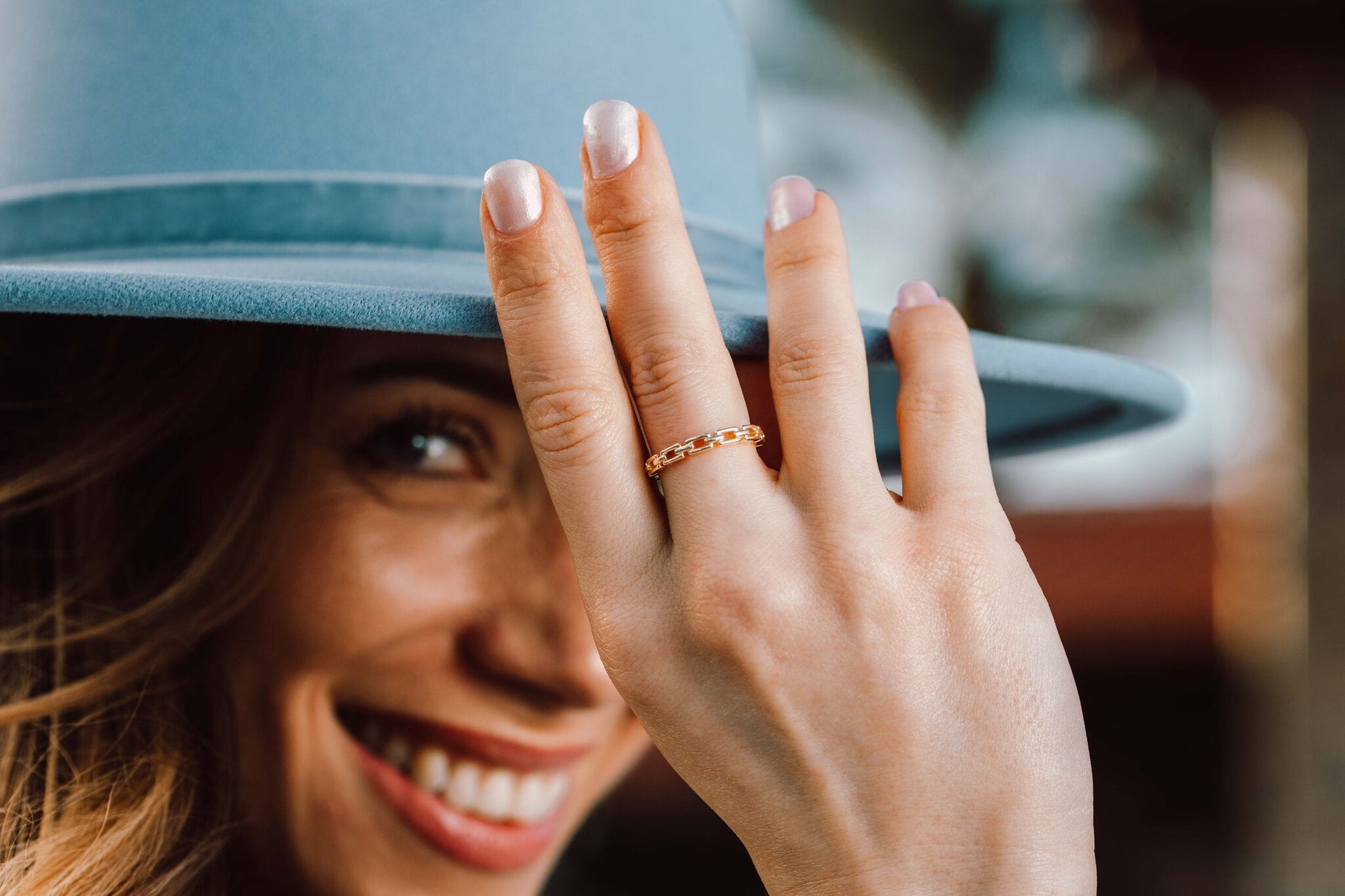 Model wearing the 14K gold Heart Ring, lifestyle shot with blue hat